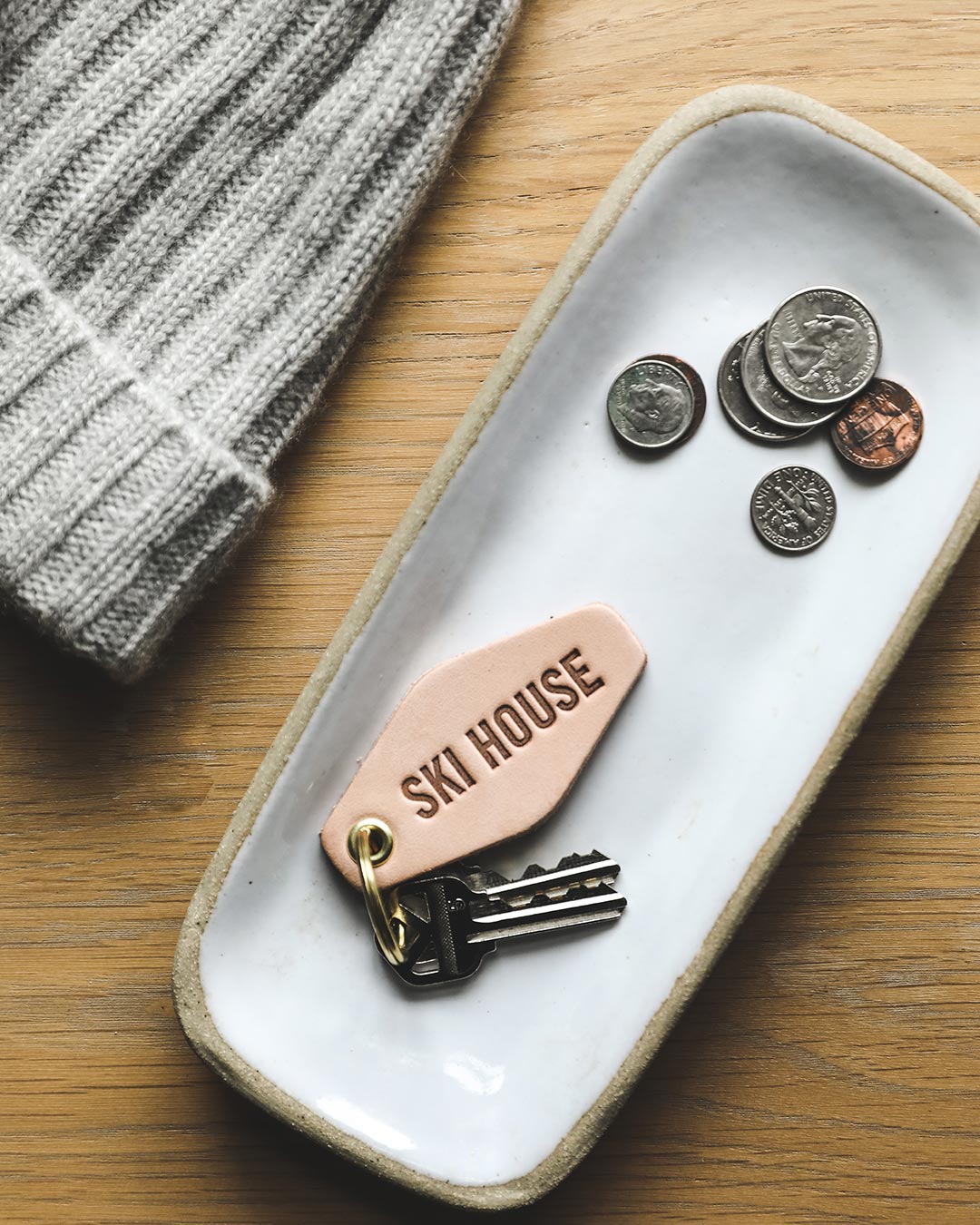 Farmhouse Pottery Ski House happy place keychain in tray with keys and coins.