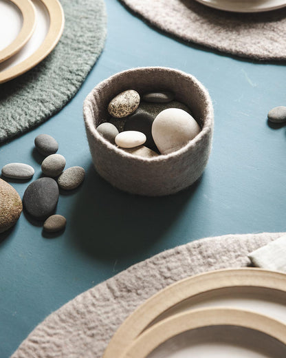 Farmhouse Pottery artisan felt nesting bowl in stone with pebbles inside.