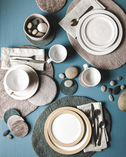 Farmhouse Pottery artisan felt nesting bowls on dinner table with pebbles inside.