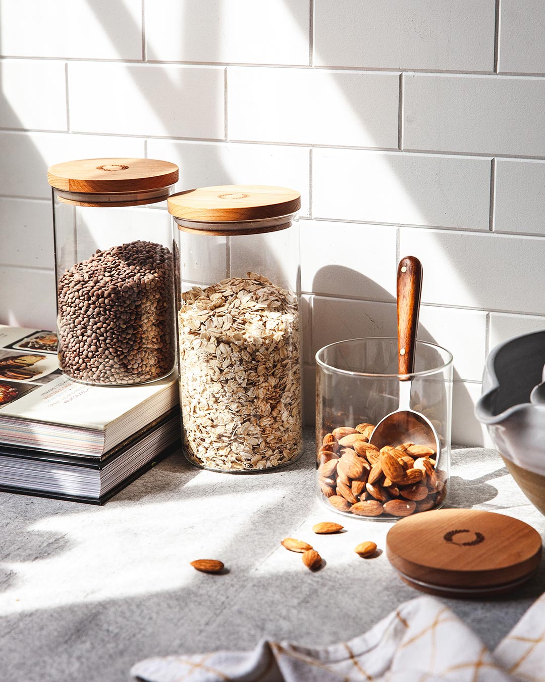 Farmhouse Pottery glass utility canisters in small medium and large on kitchen counter.