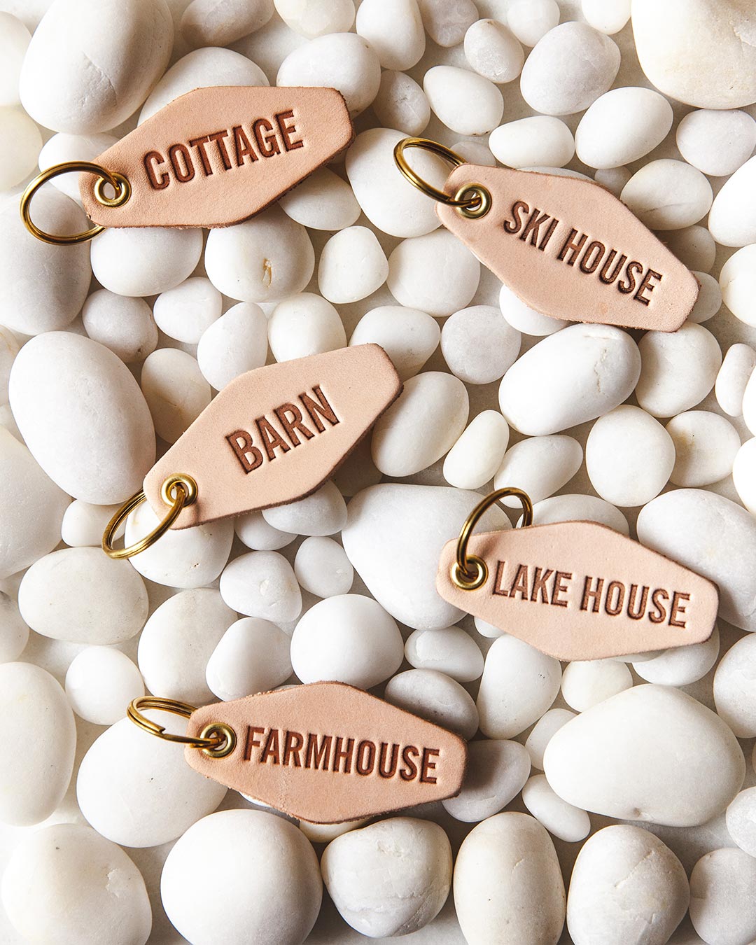 Farmhouse Pottery happy place keychains displayed on white pebbles.