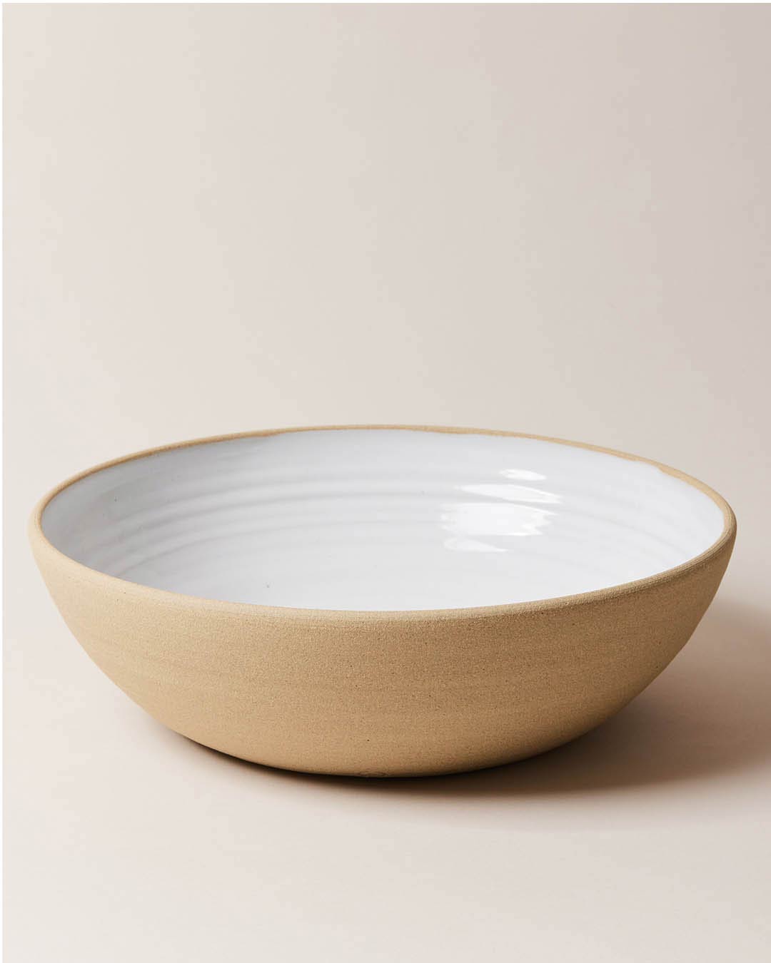 Farmhouse Pottery Harvest Serving Bowl with a light cream background. The bowl has an exposed clay outside and a milky white glaze interior.