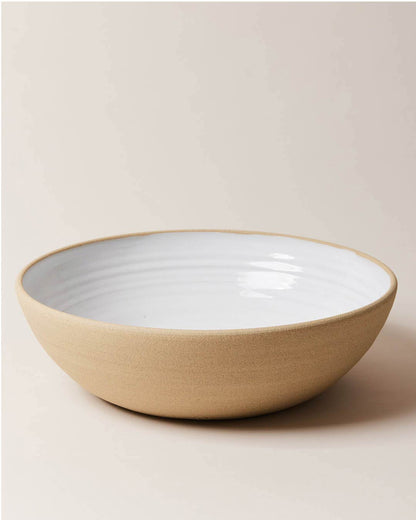 Farmhouse Pottery Harvest Serving Bowl with a light cream background. The bowl has an exposed clay outside and a milky white glaze interior.