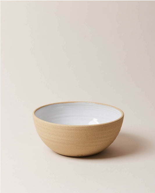 Farmhouse Pottery Harvest Serving Bowl with a light cream background. The bowl has an exposed clay outside and a milky white glaze interior.