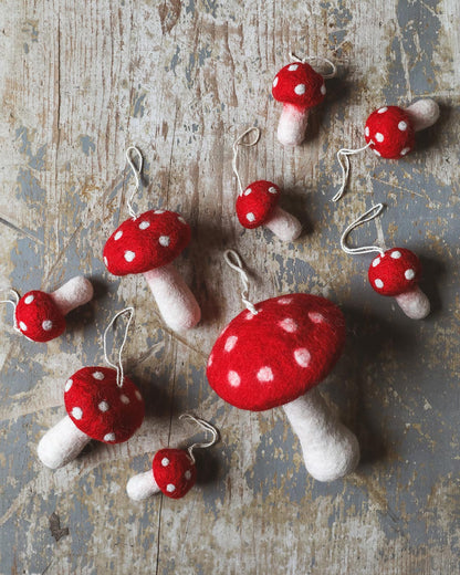Farmhouse Pottery nordic felted mushroom ornaments scattered on floor. 
