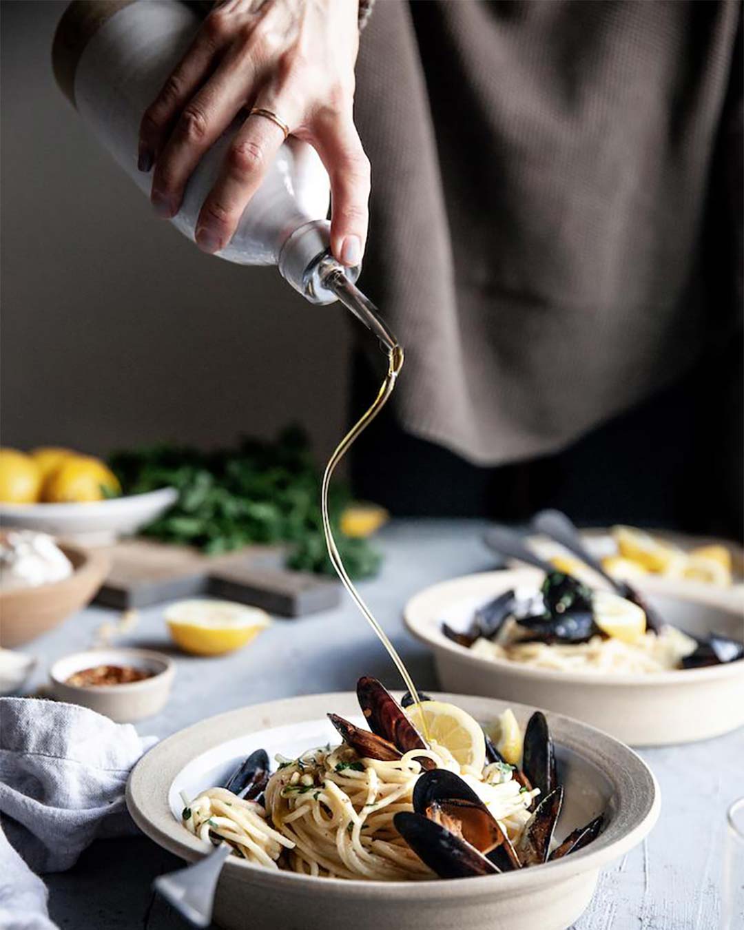 Olive Oil Bottle Medium pouring olive oil over mussels in stoneware pasta bowl