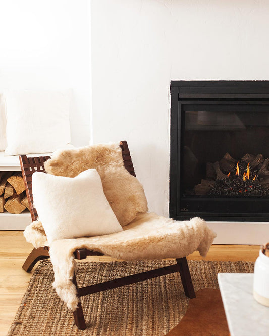 Farmhouse Oat Sheepskin on a chair in front of a fire.