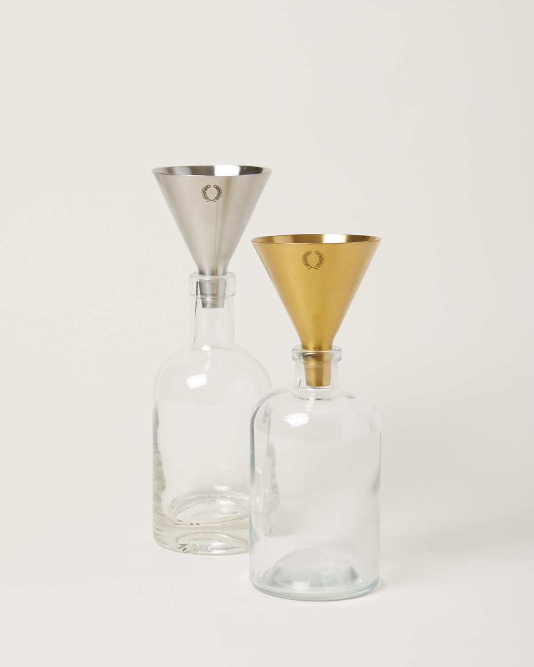 gold and silver utility funnel resting in glass bottles