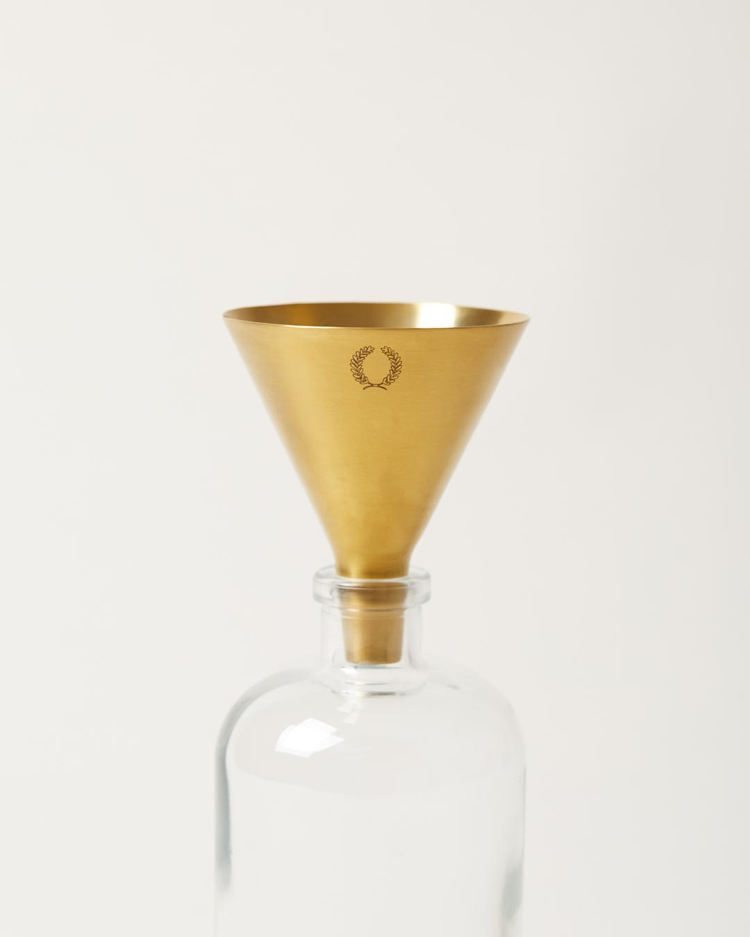 gold utility funnel resting in glass bottle 