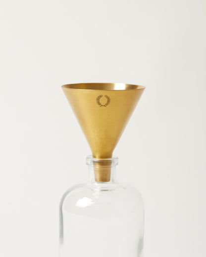 gold utility funnel resting in glass bottle 
